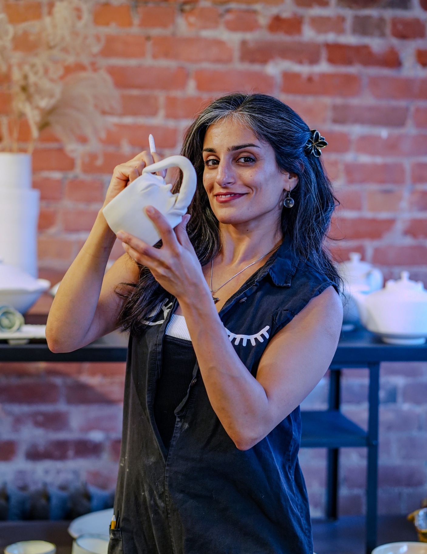 Saēna Jalalzadeh holding a freshly hand-built ceramic jug in her Toronto studio