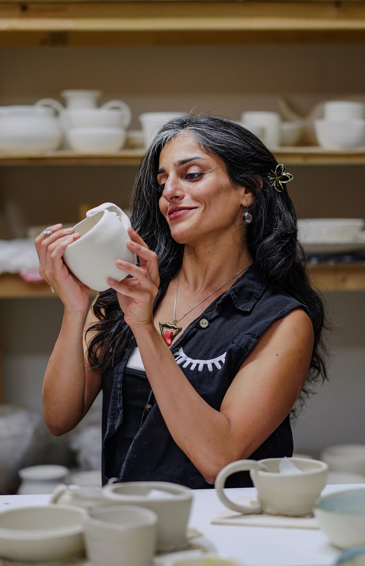 Saēna Jalalzadeh holding a hand-built vessel in her Toronto ceramics studio